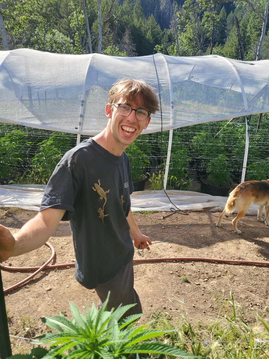 Simon Seidler in front of a row of plants, a dog beside him